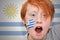 Redhead fan boy with uruguayan flag painted on his face