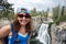 Redhead female hiker wearing a ballcap poses at Rainbow Falls in California along the John Muir Trail