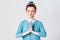 Redhead female, holding hands in namaste or prayer, keeping eyes closed while practising yoga and meditating at home alone