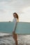 Redhead female surfer with a surfboard on the beach