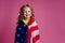 Redhead ginger charming female kid celebration independence holding american flag on a pink background in the studio