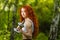 Redhead girl exercising with dumbbells at forest
