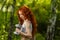 Redhead girl exercising with dumbbells at forest