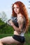 Redhead girl exercising with dumbbells at forest