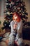 Redhead girl with fireworks in her hand. Christmas tree in a cosy home