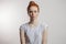 Redhead girl with hair bun and freckles isolated over grey background