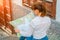 Redhead girl holds a map in her hands sitting on the stairs in front of wooden door. Street of Garachico, Tenerife on a