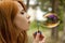 Redhead girl inflate soap bubble