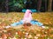 Redhead girl lies with her legs crossed in a park on a meadow strewn with autumn leaves