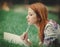 Redhead girl with notebook on green lawn