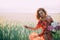 Redhead girl in a red dress with a bouquet of peonies dancing joyful in a wheat field in summer at sunset. Soft focus