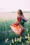 Redhead girl in a red dress with a bouquet of peonies dancing joyful in a wheat field in summer at sunset. Soft focus