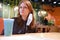 Redhead girl in a removed medical mask sits in an empty cafe after quarantine. Deserted restaurant after the completion of the