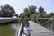 Redhead girl staying on a wooden dock above Danube river near trees.