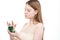 Redhead girl takes cosmetic cream out of jar on white background.