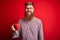 Redhead Irish man with beard drinking a cup of hot coffee over red background with a happy face standing and smiling with a