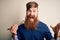 Redhead Irish man with beard eating green maki sushi using chopsticks over yellow background very happy and excited, winner