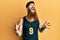 Redhead man with long beard wearing basketball uniform crazy and mad shouting and yelling with aggressive expression and arms