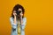 Redhead photographer covering face with digital camera isolated on orange