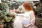 Redhead pregnant girl stroking her belly. On the background of the yard with plants. Summer