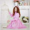 Redhead pretty woman in a pink dress sitting in sunny spring day at studioÑŽ