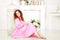 Redhead pretty woman in a pink dress sitting in sunny spring day at studioÑŽ
