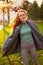 Redhead smiling pretty woman walking in park on sunny autumn day. Elegant female poses in stylish authentic outfit has