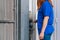 Redhead woman in a blue shirt using a screwdriver while repairing an electrical box in the garage