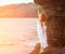 Redhead woman in dress standing on beach.