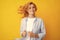 Redhead woman with movement hair. Studio shot of carefree redhead woman smiles cheerfully isolated over vivid yellow