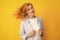 Redhead woman with movement hair. Studio shot of carefree redhead woman smiles cheerfully  over vivid yellow