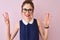 Redhead woman with pigtail wearing elegant dress and glasses over isolated pink background showing and pointing up with fingers