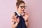 Redhead woman with pigtail wearing elegant dress and glasses over  pink background disgusted expression, displeased and