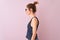 Redhead woman with pigtail wearing striped t-shirt standing over  pink background looking to side, relax profile pose with