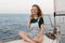 A redhead woman posing sitting on a yacht in the middle of the sea during the summer weekend