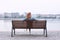 Redhead woman sitting on bench at riverbank back view