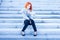 Redhead woman sitting outside on the stairs and watching time