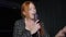 Redhead young Caucasian talented woman singing with microphone performing on stage indoors. Portrait of confident