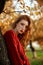 Redhead young woman in a red sweater walks in the park. Autumn beauty portrait of a fashionable Red-haired woman at sunset