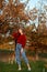 Redhead young woman in a red sweater walks in the park. Autumn beauty portrait of a fashionable Red-haired woman at sunset