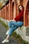 Redhead young woman in a red sweater walks in the park. Autumn beauty portrait of a fashionable Red-haired woman at sunset