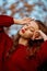 Redhead young woman in a red sweater walks in the park. Autumn beauty portrait of a fashionable Red-haired woman at sunset