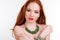 Redheaded girl is wearing green necklace