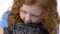 Redheaded little girl with curly hair is gently holding grey chinchilla at white background. Slow motion. Close up