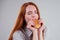 Redheared hungry woman in striped shirt eating USA burger visa traveler white background studio