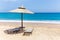 Reed beach umbrella with loungers on beach at sea