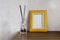 Reed diffusor and yellow picture frame on the table. Cozy home atmosphere. Relaxation with aromatherapy. Mock up photo