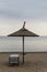 Reed Parasol With Sun Loungers on Sandy Beach. Umbrella and Sunbeds on Gloomy Weather and Calm Sea. Reed Umbrella and Easy