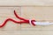 Reef knot made with red rope on wooden background.