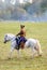 Reenactor dressed as Napoleonic war soldier rides a white horse.